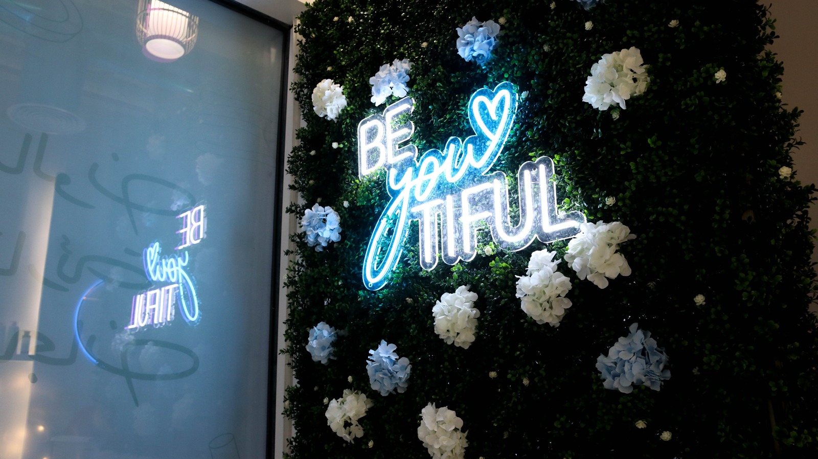 Be-you-tiful neon sign on flower wall at Qareat Al Fenjan